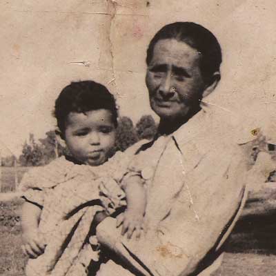 Close up of Clara Martínez holding her grandson, Robert Marron Romero. Links to Explore People.